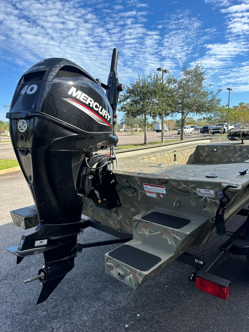 Slide: The Image of 2025 Tracker Grizzly 1654 T Sportsman boat with Mercury outboard motor, parked outdoors. - 3