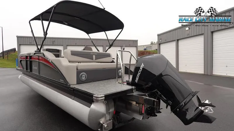 Slide: The Image of 2025 Barletta C22U pontoon boat with Mercury outboard motor, parked near storage units. - 7