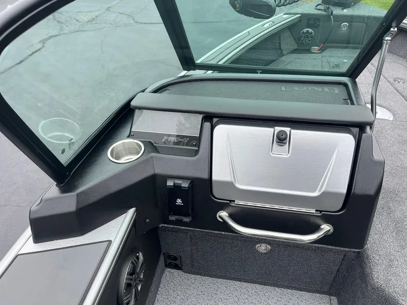 Slide: The Image of 2025 Lund 1975 Pro-V boat dashboard with storage compartment and cup holder. - 14