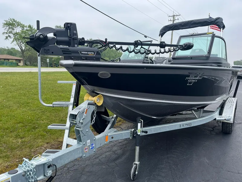 Slide: The Image of 2025 Lund 1975 Pro-V boat on trailer, parked outdoors, featuring sleek black design. - 3