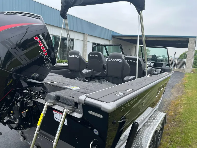 Slide: The Image of 2025 Lund 1975 Pro-V boat with Mercury engine, parked outdoors near a building. - 5
