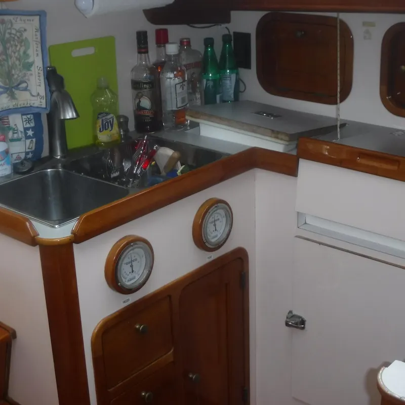 Slide: The Image of 1998 Legacy 40' Flybridge yacht kitchen with sink, bottles, and wooden cabinets. - 29