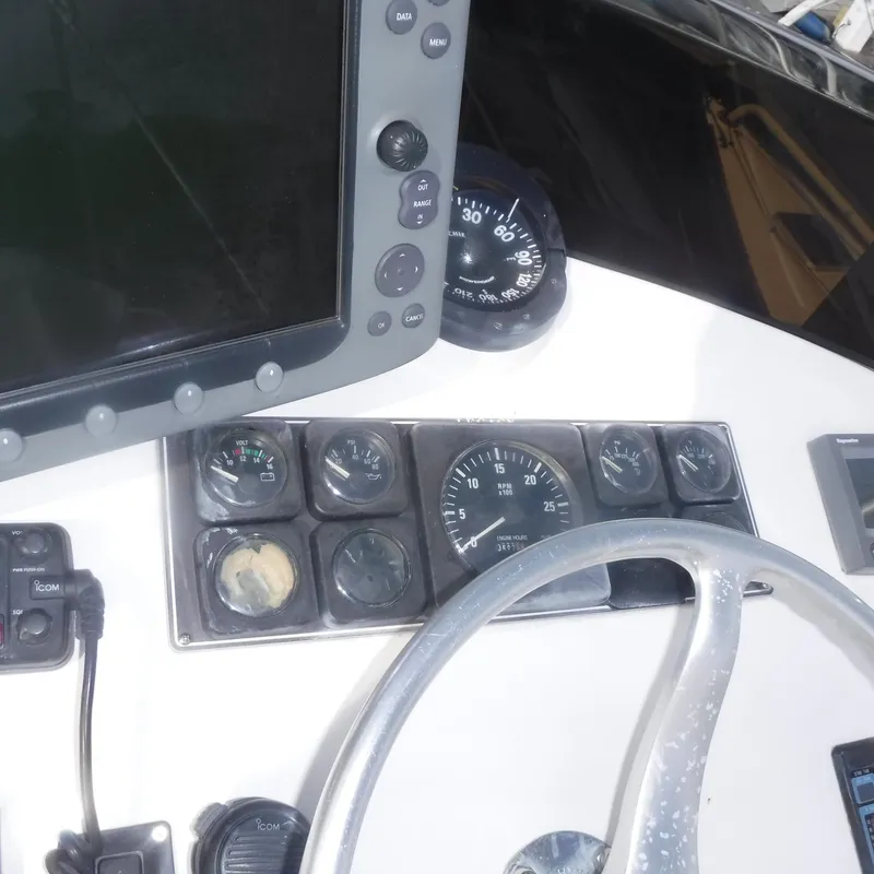 Slide: The Image of Legacy 40' Flybridge 1998 helm with gauges, steering wheel, and navigation equipment. - 43