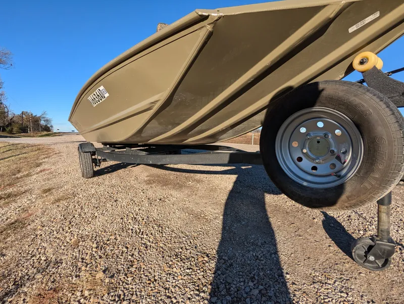 Slide: The Image of 2023 Tracker Grizzly 1648 SC boat on trailer, parked on gravel road. - 11