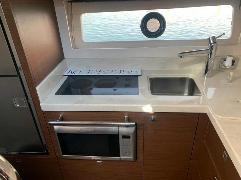 Slide: The Image of 2014 Sea Ray 410 Sundancer yacht kitchen with stove, sink, and microwave. - 30