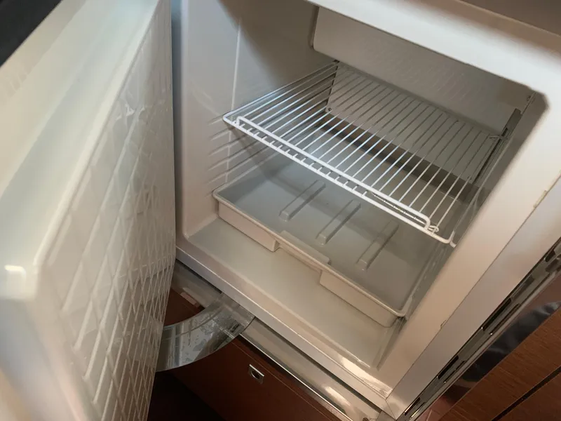 Slide: The Image of Open fridge inside 2014 Sea Ray 410 Sundancer yacht, showing empty shelves. - 36