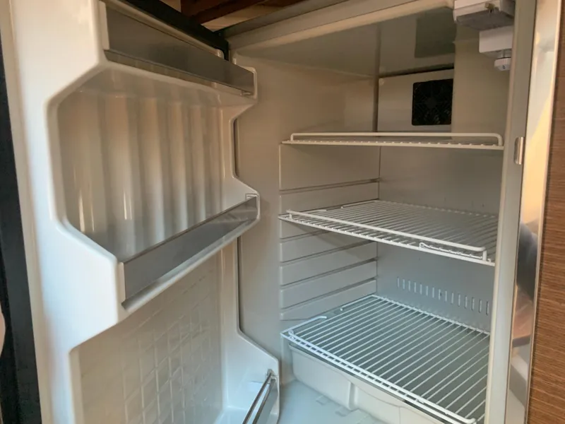 Slide: The Image of Empty refrigerator inside 2014 Sea Ray 410 Sundancer yacht, featuring wire shelves and door storage. - 37