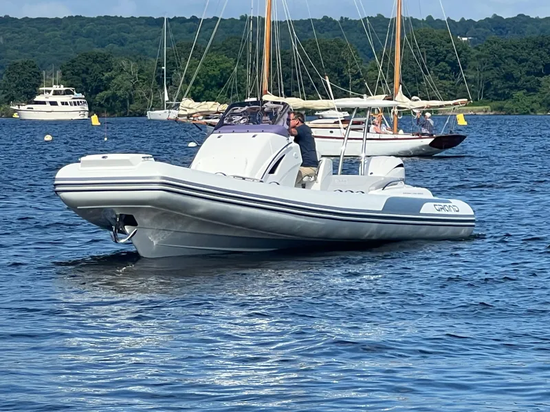 Slide: The Image of 2024 Grand Goldenline 850 boat cruising on a scenic lake with sailboats in the background. - 2