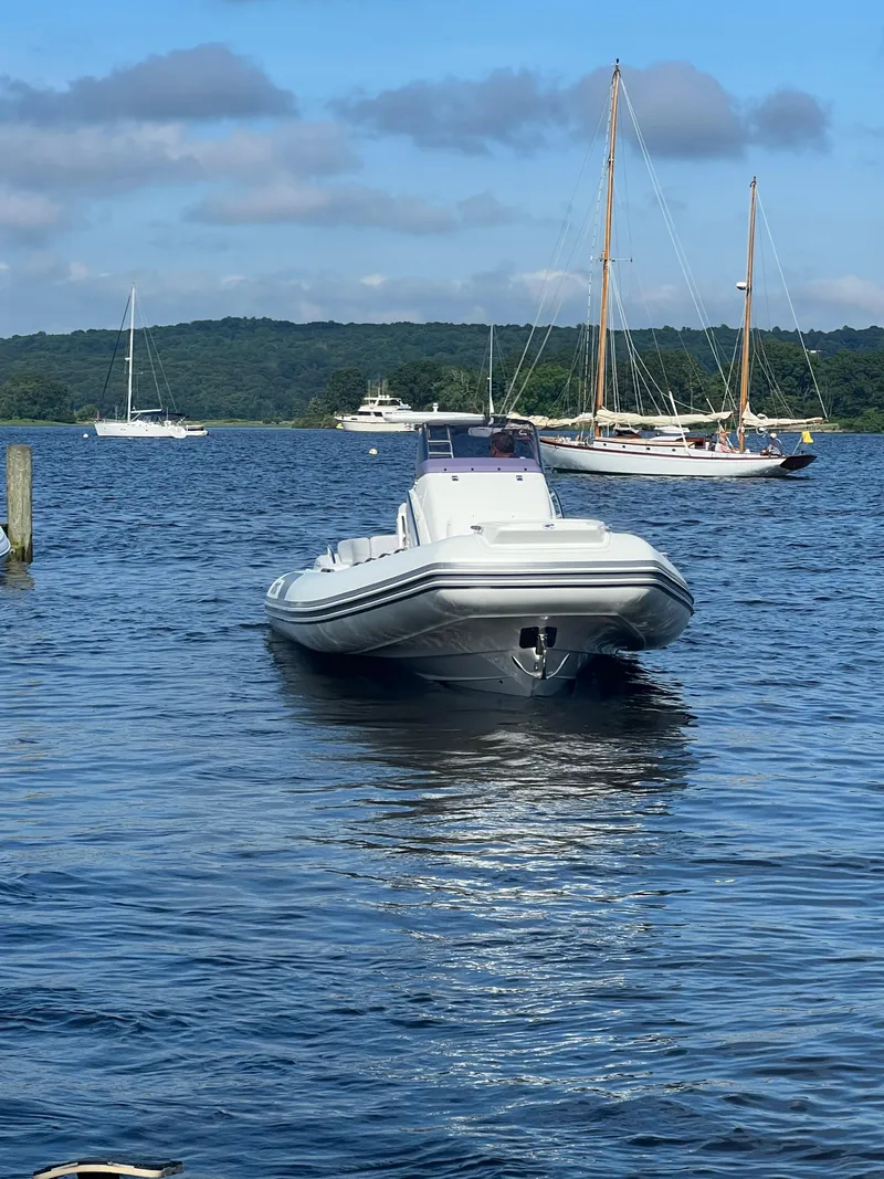 Slide: The Image of 2024 Grand Goldenline 850 boat on a serene lake with sailboats in the background. - 3