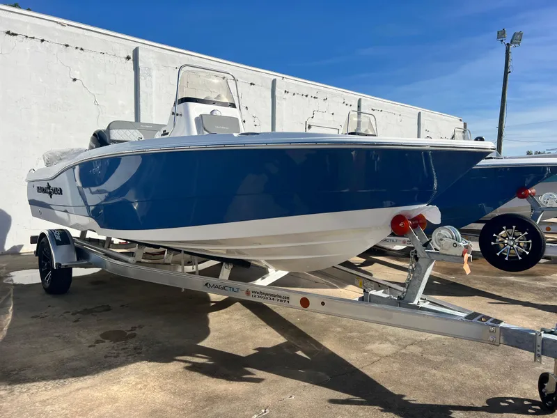 Slide: The Image of 2025 NauticStar 191 Hybrid boat on trailer, blue and white design, parked outdoors. - 3