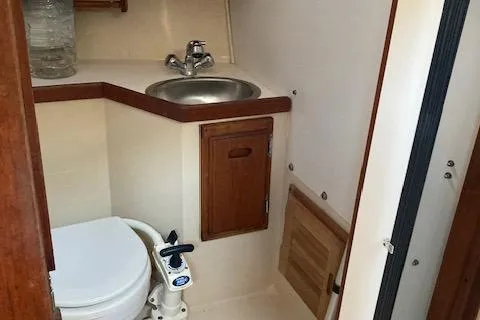 Slide: The Image of 1989 Catalina 30 yacht bathroom with sink, toilet, and wooden cabinetry. - 12