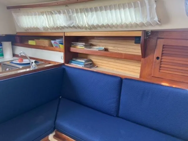 Slide: The Image of Interior of 1989 Catalina 30 sailboat with blue seating and wooden shelves. - 19