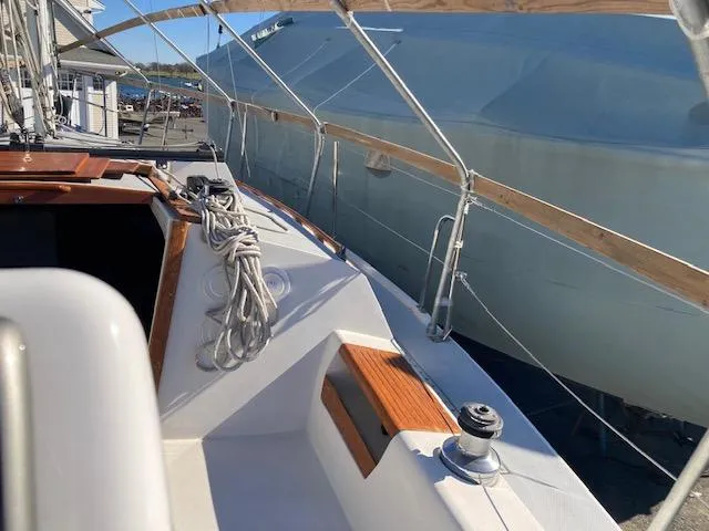 Slide: The Image of 1989 Catalina 30 sailboat deck with ropes and winch, docked beside a covered vessel. - 2