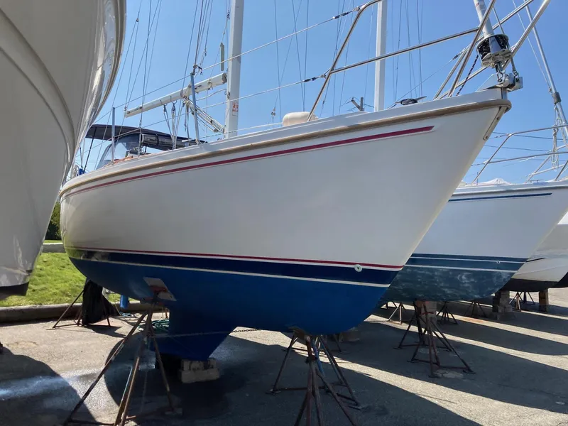 Slide: The Image of 1989 Catalina 30 sailboat on stands, white hull with blue bottom, in a marina. - 27