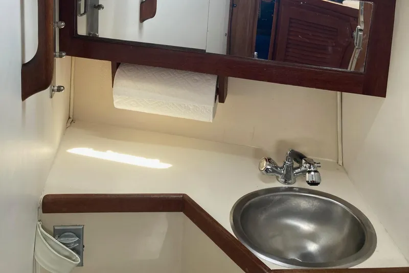 Slide: The Image of 1989 Catalina 30 yacht bathroom with sink, mirror, and paper towel holder. - 31
