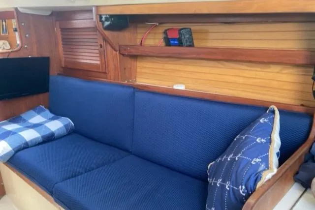 Slide: The Image of Interior of 1989 Catalina 30 sailboat with blue cushioned seating and nautical-themed pillows. - 39