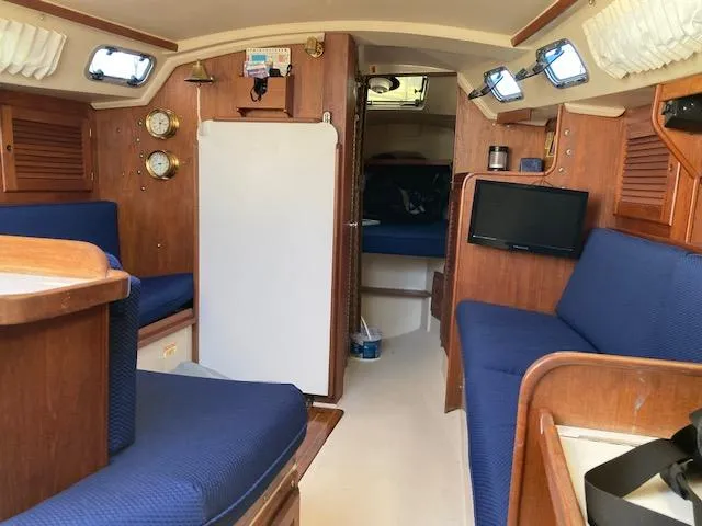 Slide: The Image of Interior of a 1989 Catalina 30 sailboat with blue seating and wooden accents. - 9