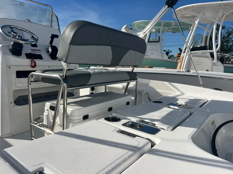 Slide: The Image of 2025 NauticStar 211 Hybrid boat interior with seating and console, under clear blue sky. - 6