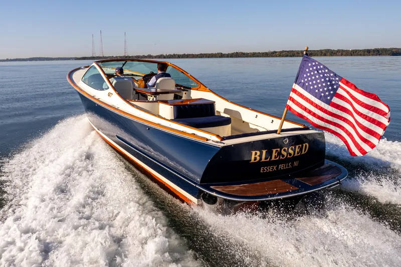 Slide: The Image of 2003 Hinckley Talaria 29 Runabout cruising with American flag on open water. - 12