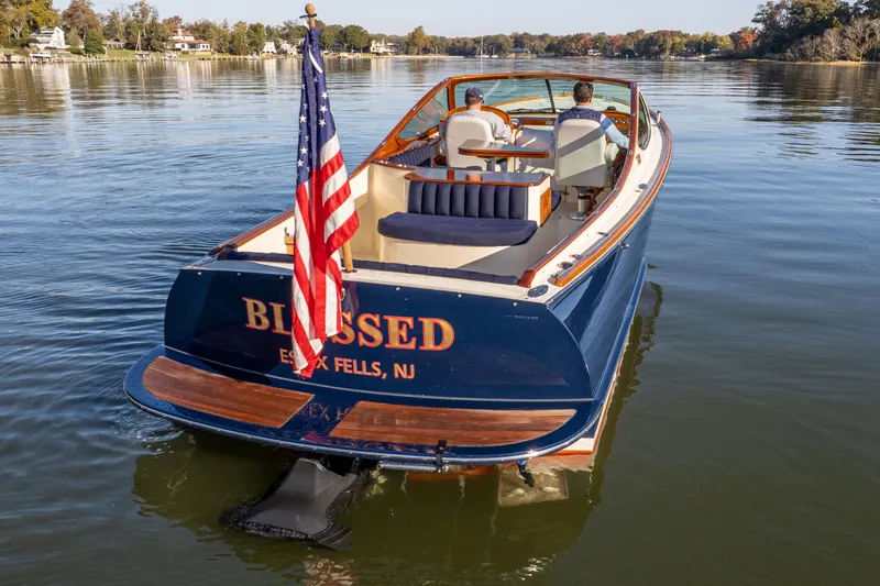 Slide: The Image of 2003 Hinckley Talaria 29 Runabout on calm water, displaying American flag. - 13