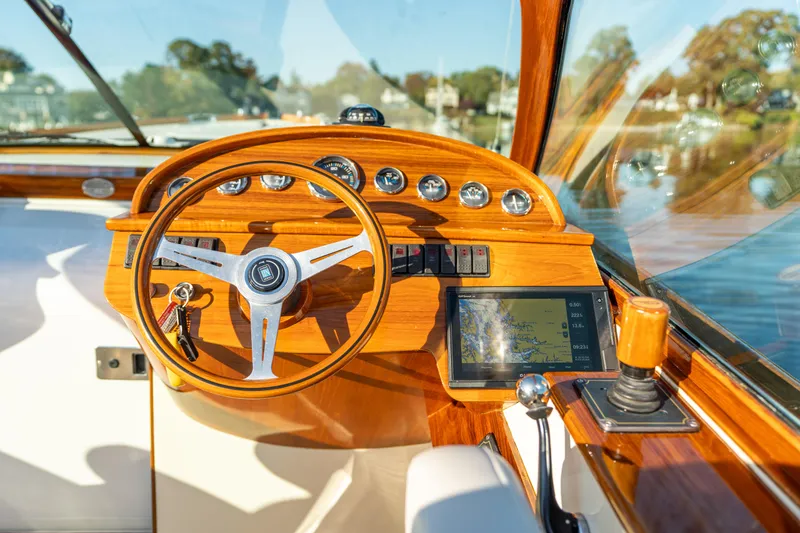 Slide: The Image of 2003 Hinckley Talaria 29 Runabout cockpit with wooden steering wheel and navigation instruments. - 18