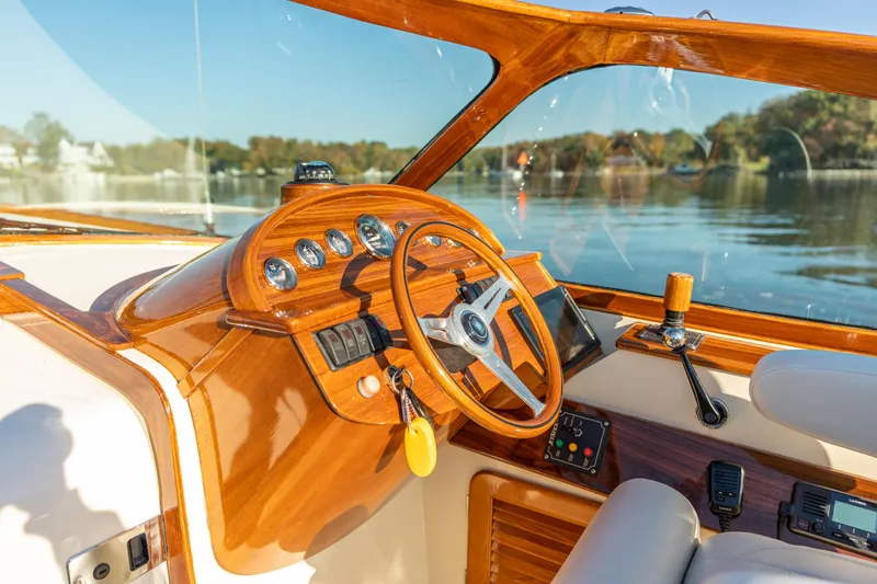 Slide: The Image of 2003 Hinckley Talaria 29 Runabout cockpit with wooden steering wheel and dashboard controls. - 19
