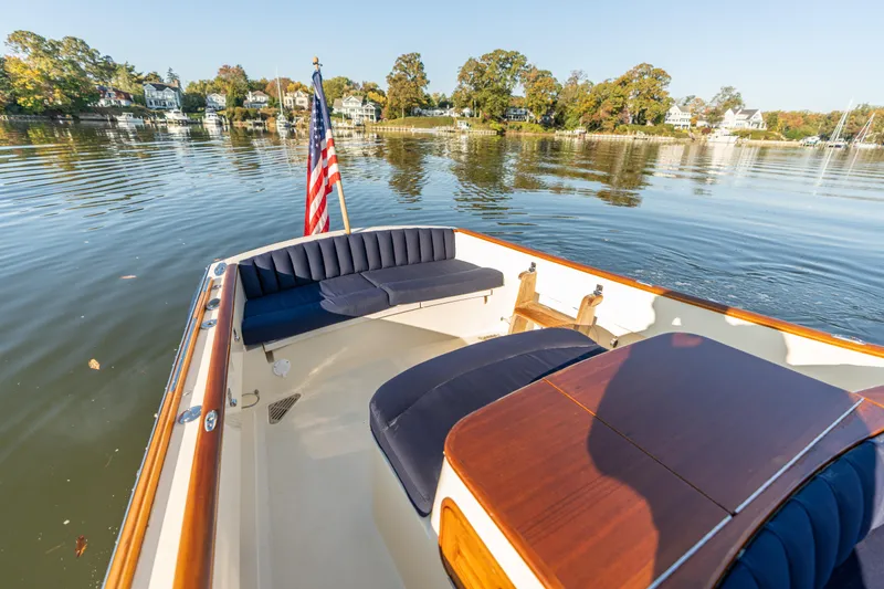 Slide: The Image of 2003 Hinckley Talaria 29 Runabout on calm water, featuring elegant seating and American flag. - 28