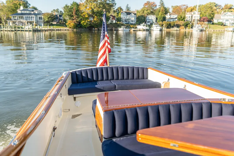 Slide: The Image of 2003 Hinckley Talaria 29 Runabout on calm water, featuring elegant seating and American flag. - 30