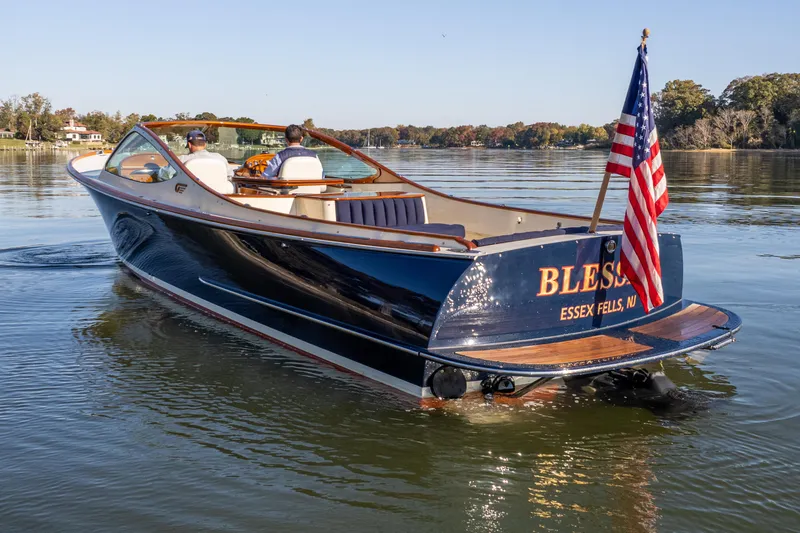 Slide: The Image of 2003 Hinckley Talaria 29 Runabout on calm water, displaying American flag. - 5