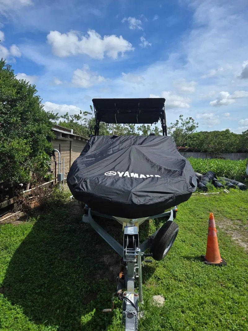 Slide: The Image of 2013 Yamaha SX240 HO boat covered, parked on grass with blue sky background. - 4