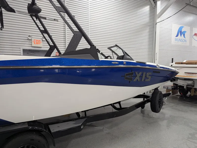Slide: The Image of 2025 Axis A225 boat in showroom, blue and white design, on trailer. - 3