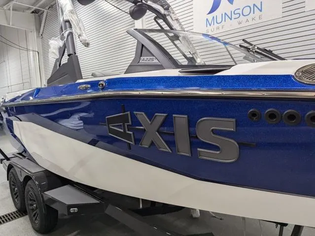 Slide: The Image of 2025 Axis A225 boat in showroom, blue and white design, Munson Surf Wake branding. - 4