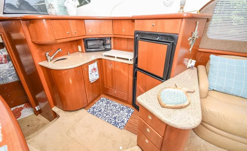 Slide: The Image of 2007 Silverton 35 Motor Yacht interior with kitchenette, wood cabinetry, and compact appliances. - 16