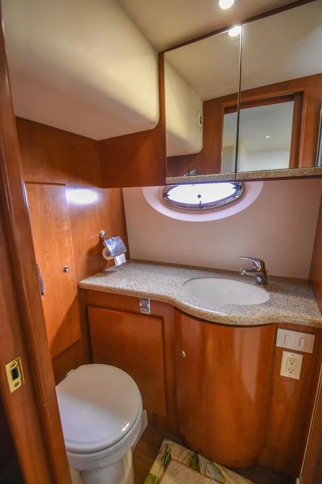 Slide: The Image of 2007 Silverton 35 Motor Yacht bathroom with wood cabinetry and oval window. - 17