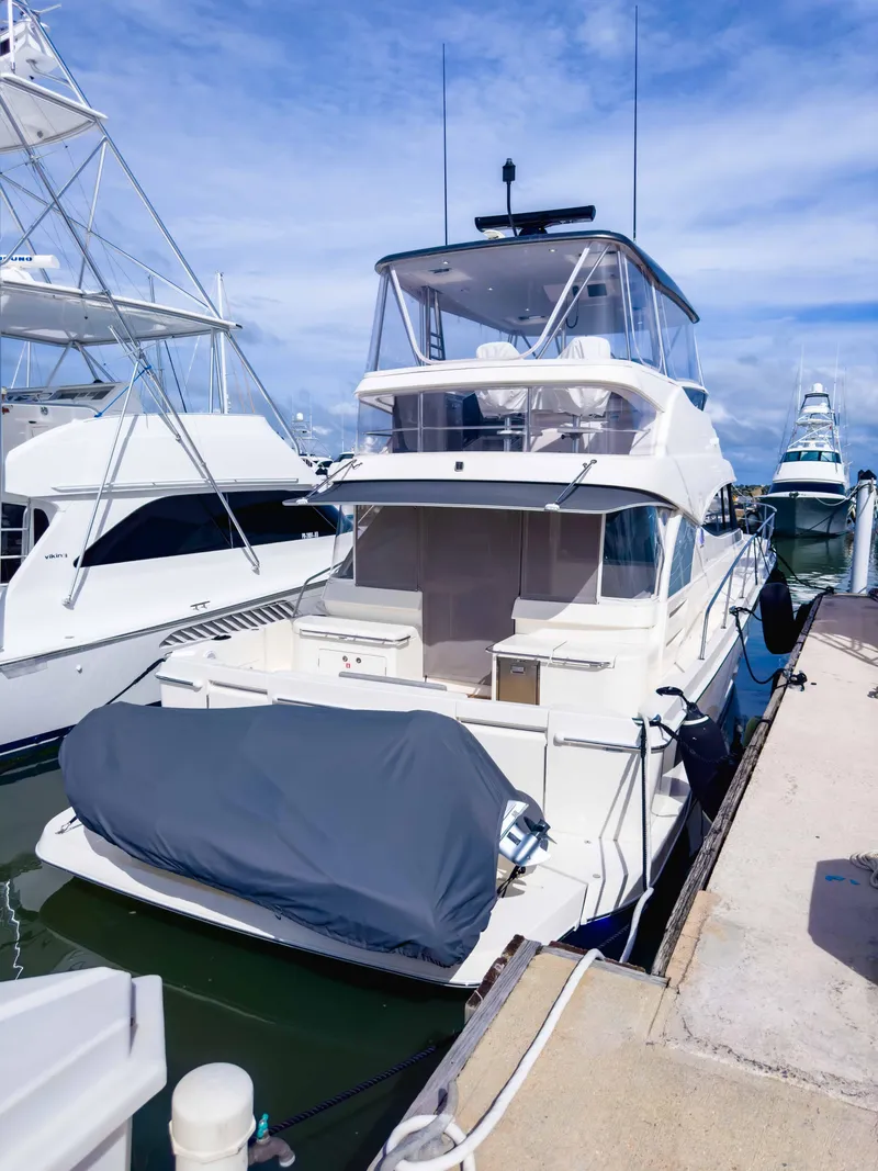 The Image of 2024 Riviera SMY 46 yacht docked at marina under clear blue sky. - 0