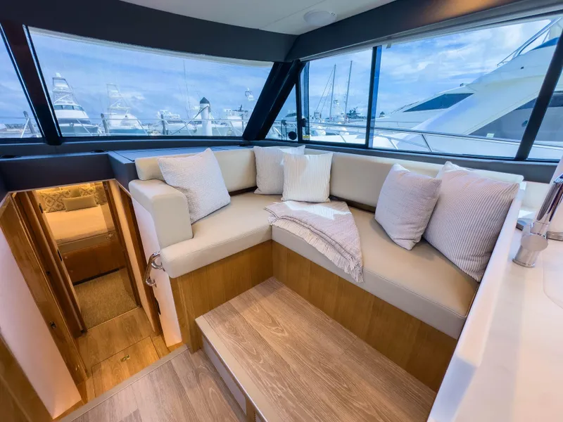 Slide: The Image of 2024 Riviera SMY 46 yacht interior with cozy seating and marina view. - 10