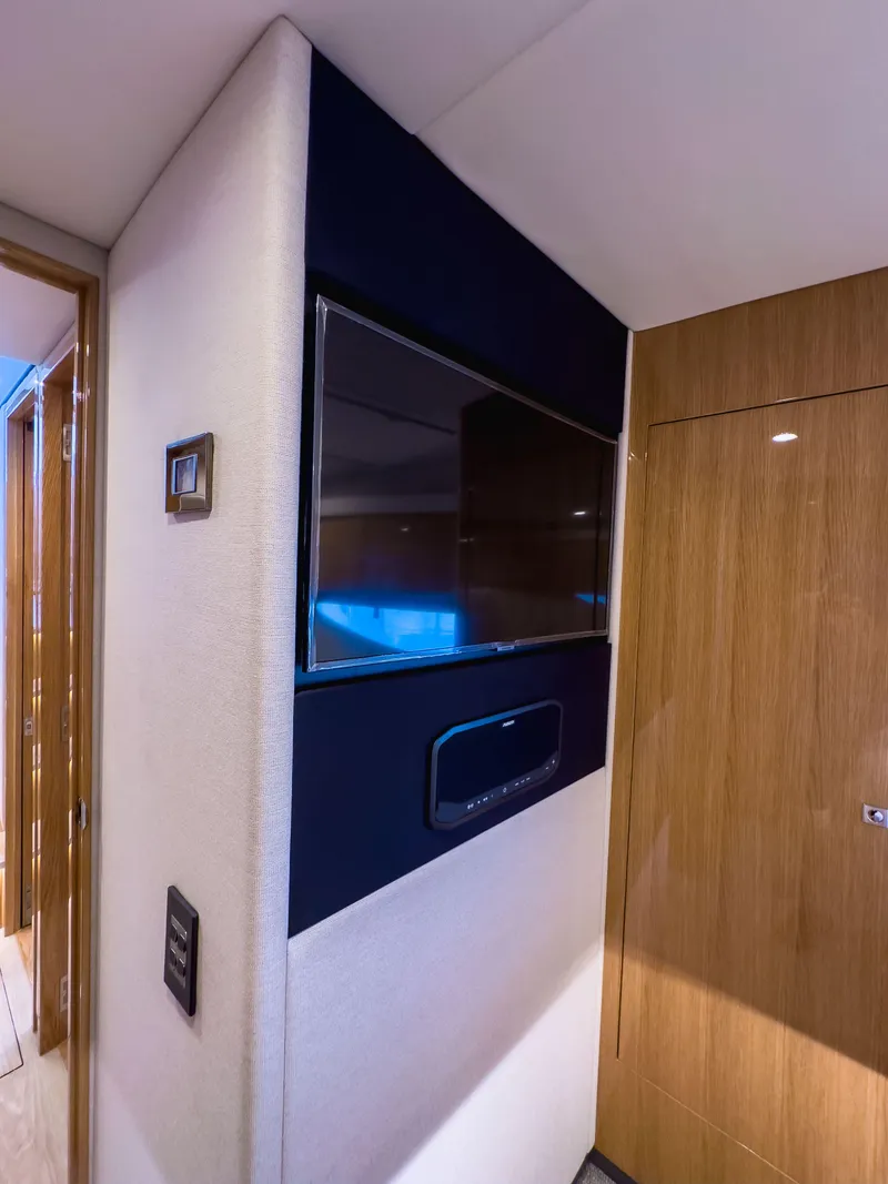 Slide: The Image of 2024 Riviera SMY 46 yacht interior with mounted TV and wooden paneling. - 20
