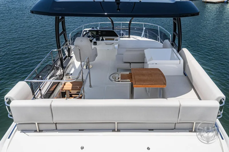 Slide: The Image of Luxurious 2025 Prestige F4.9 yacht deck with seating, table, and helm, overlooking serene water. - 13