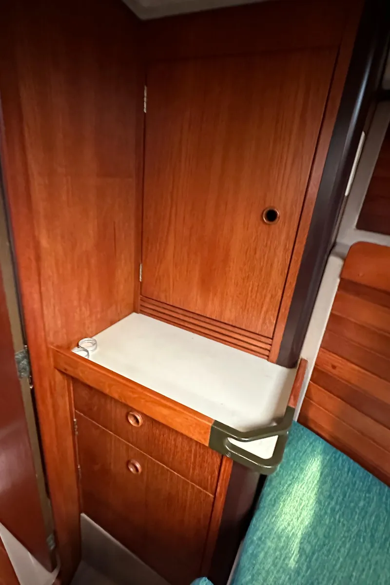 Slide: The Image of 1986 C&C 41 yacht interior with wooden cabinetry and teal upholstery. - 23