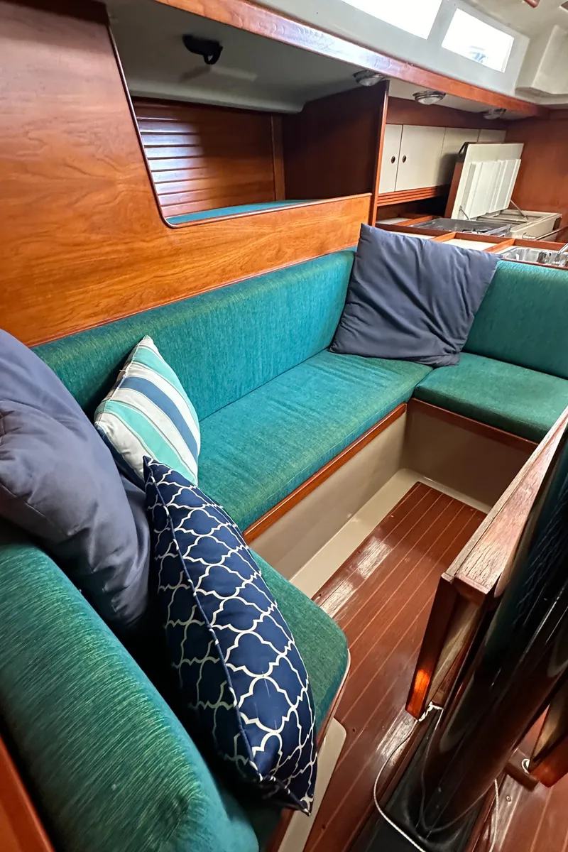 Slide: The Image of 1986 C&C 41 sailboat interior with green seating and decorative pillows. - 27