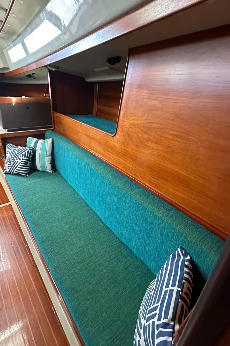 Slide: The Image of 1986 C&C 41 sailboat interior with teal seating and decorative pillows. - 28