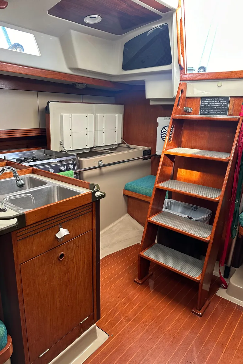 Slide: The Image of 1986 C&C 41 yacht interior with wooden cabinetry and compact kitchen area. - 37