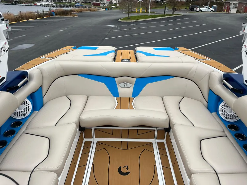 Slide: The Image of 2025 Centurion Fe22 boat interior with beige and blue seating in a parking lot. - 11