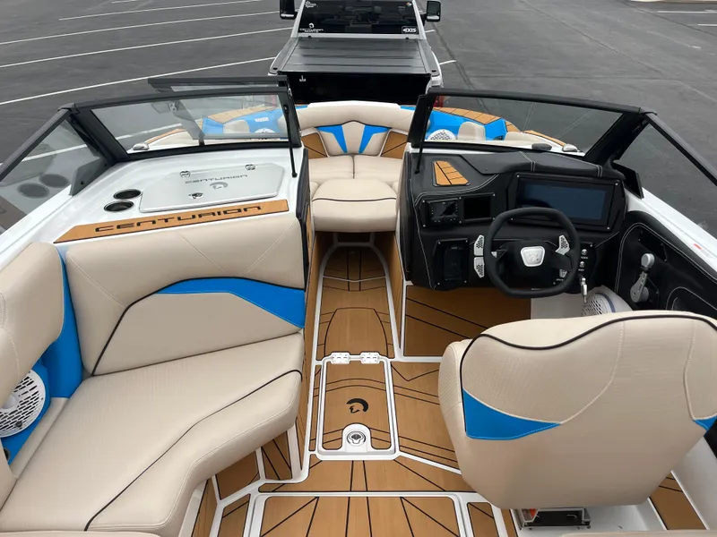 Slide: The Image of 2025 Centurion Fe22 boat interior with beige and blue seating, modern dashboard, and wood accents. - 12