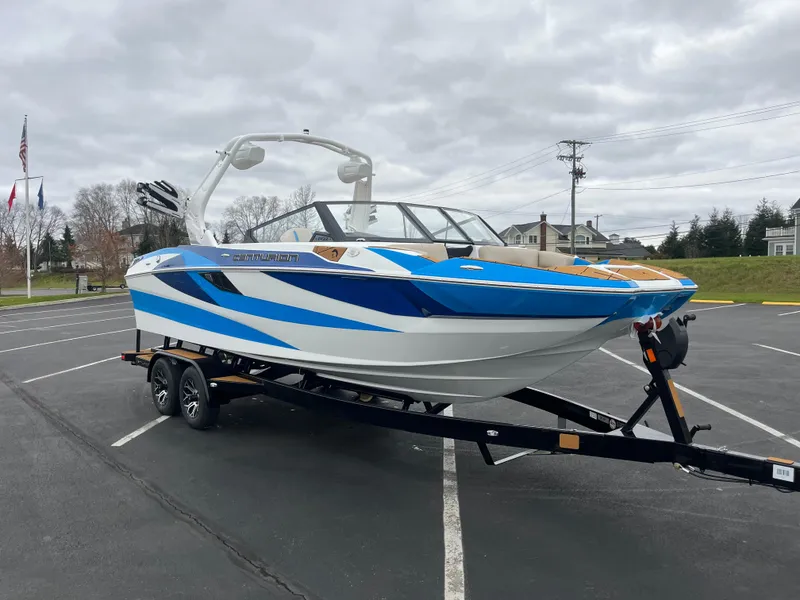 Slide: The Image of 2025 Centurion Fe22 boat with blue and white design on a trailer in a parking lot. - 3