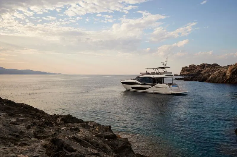 Slide: The Image of Prestige F5.7 yacht cruising near rocky coastline, serene sea, 2026 model. - 6