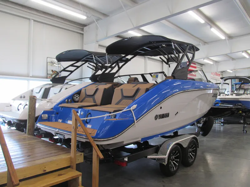 Slide: The Image of 2025 Yamaha Boats 222XD in showroom, blue and white design, on trailer. - 2