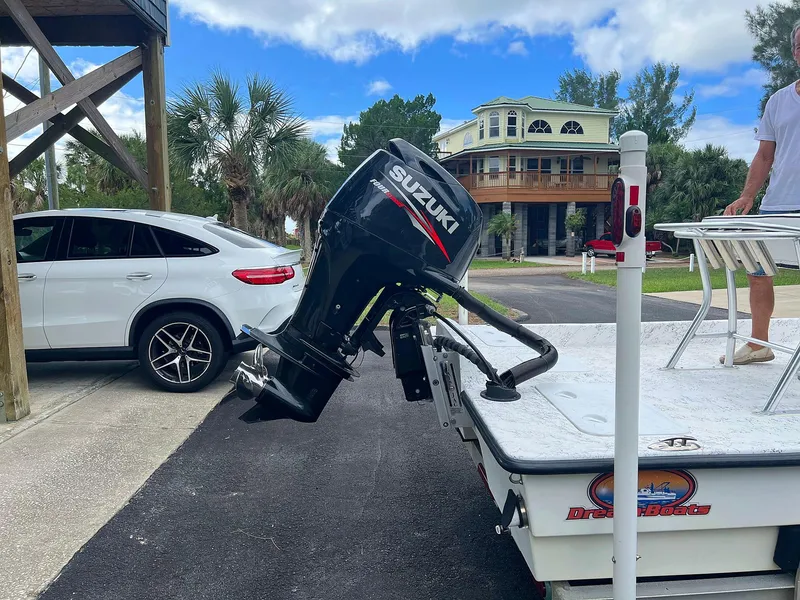 Slide: The Image of Dream Boats C-18 with Suzuki outboard motor, parked near a house and car. - 27