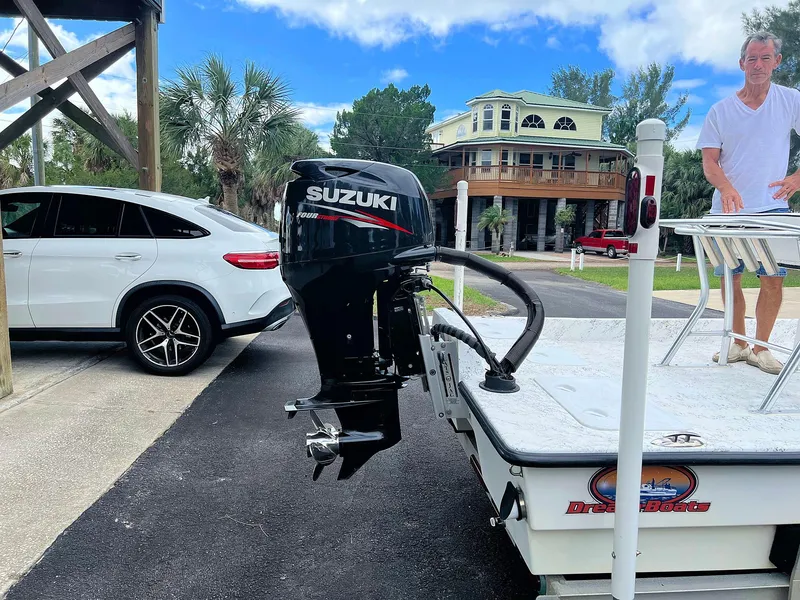Slide: The Image of 2013 Dream Boats C-18 with Suzuki outboard motor parked near a house and car. - 9