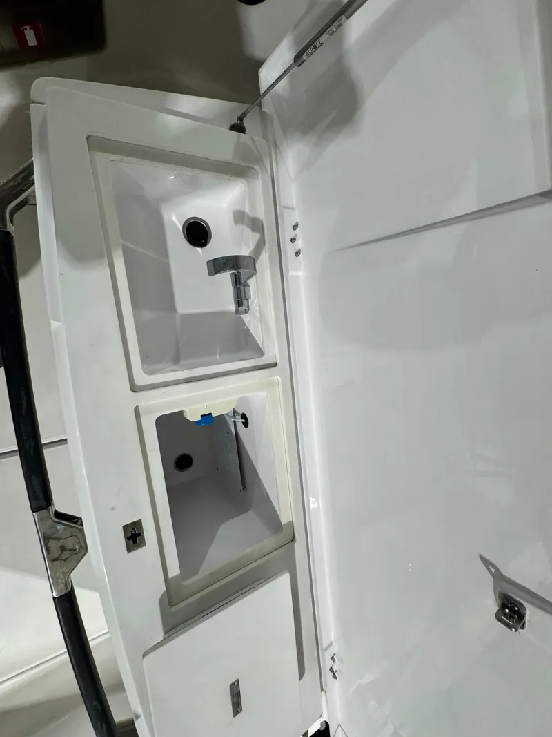 Slide: The Image of 2020 Axopar 37 Cross Cabin BRABUS storage compartment, featuring a drain and white interior. - 35